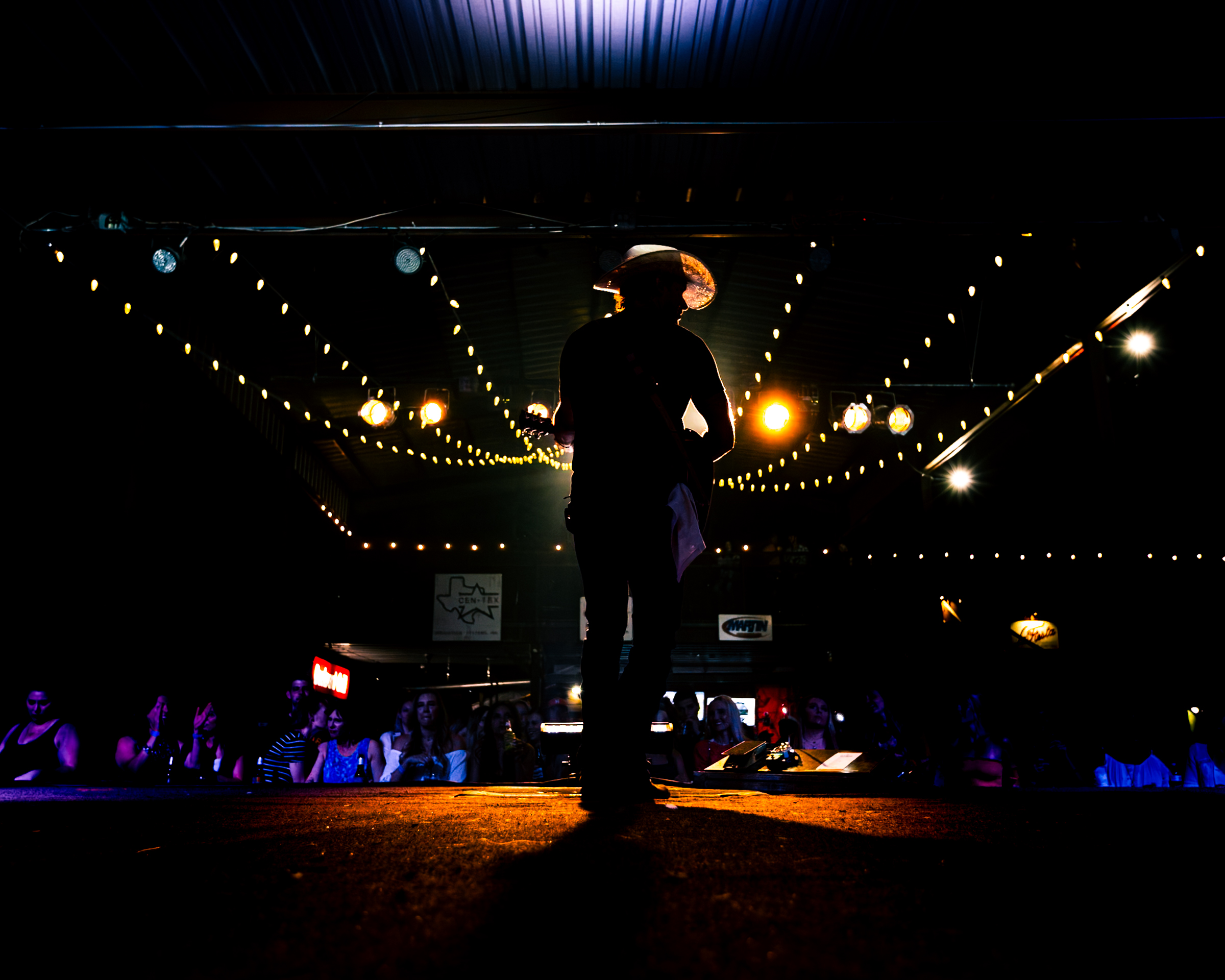 A silhouetted performer viewed from behind the stage