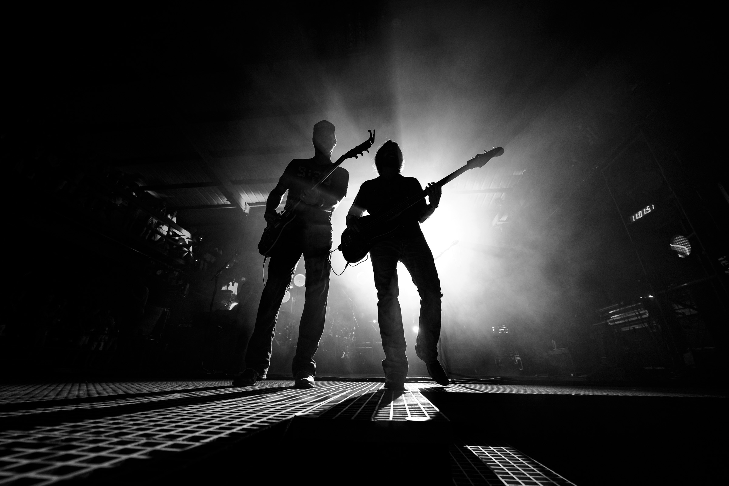 Two musicians silhouetted together against bright stage lights