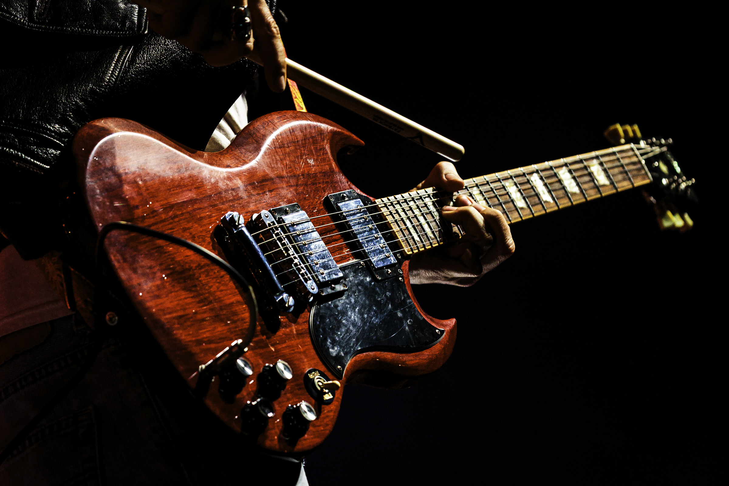 A guitarist playing with a drumstick