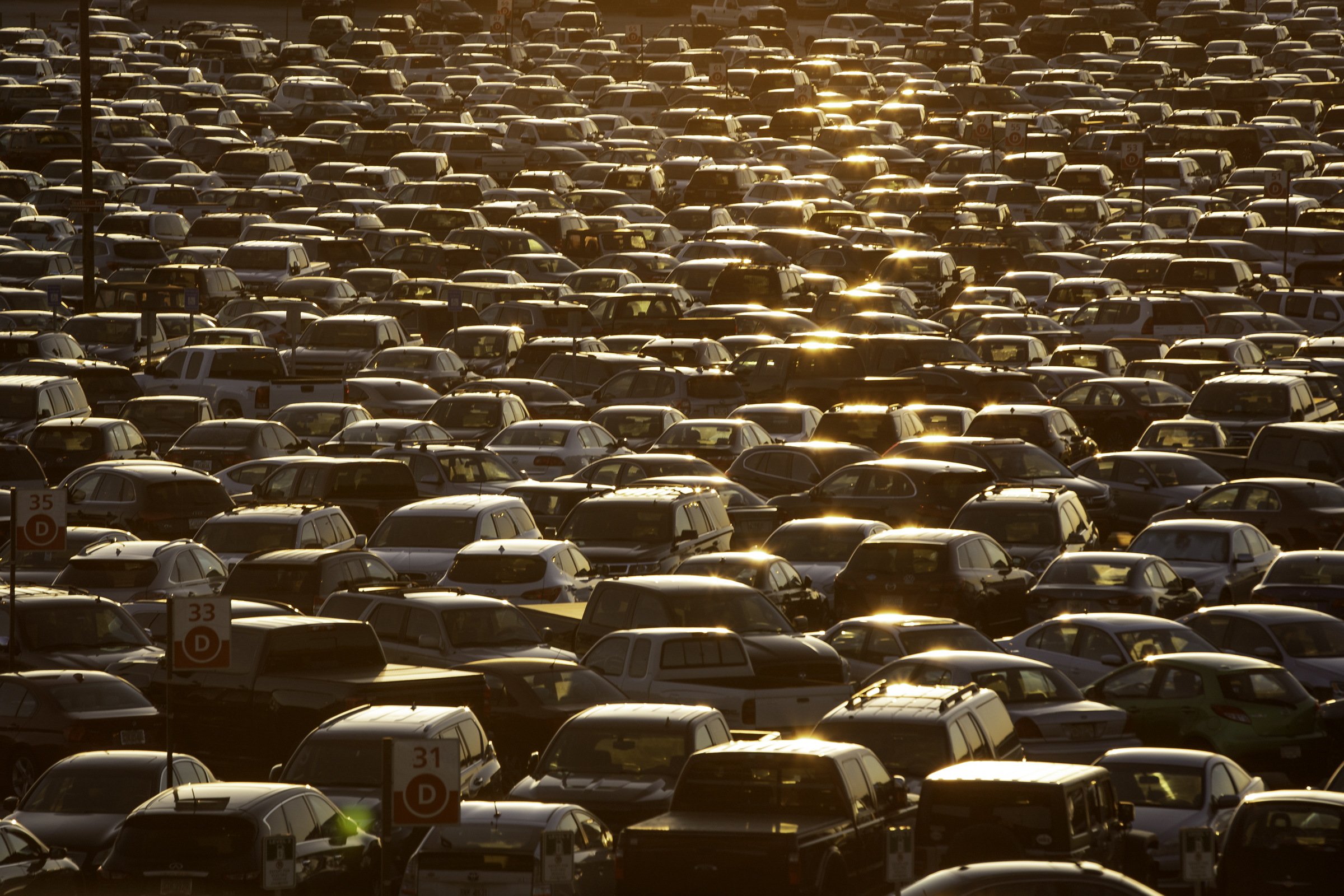 Rows of parked cars illuminated by evening sunlight at an airport