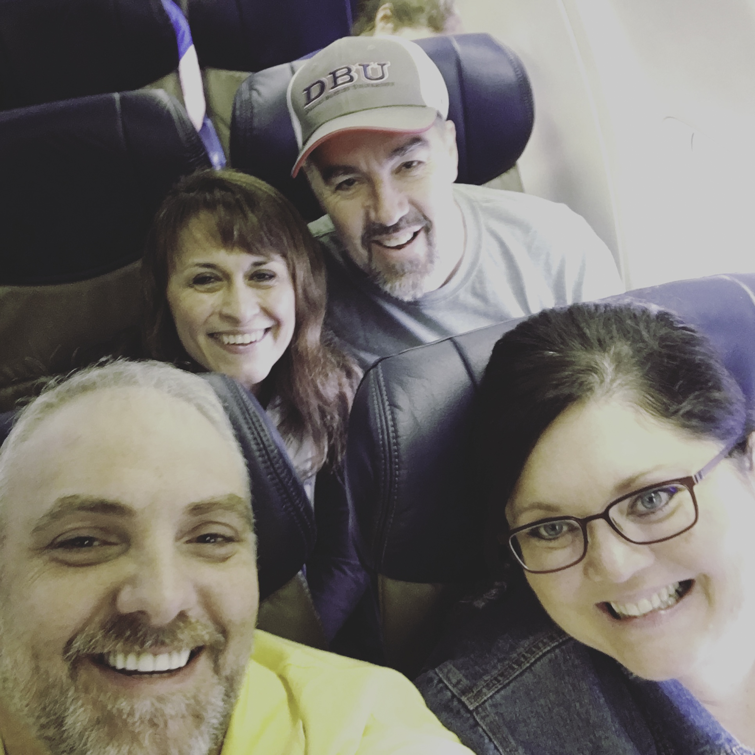 Tim, Melissa, Greg, and Mitzi smiling together on the airplane