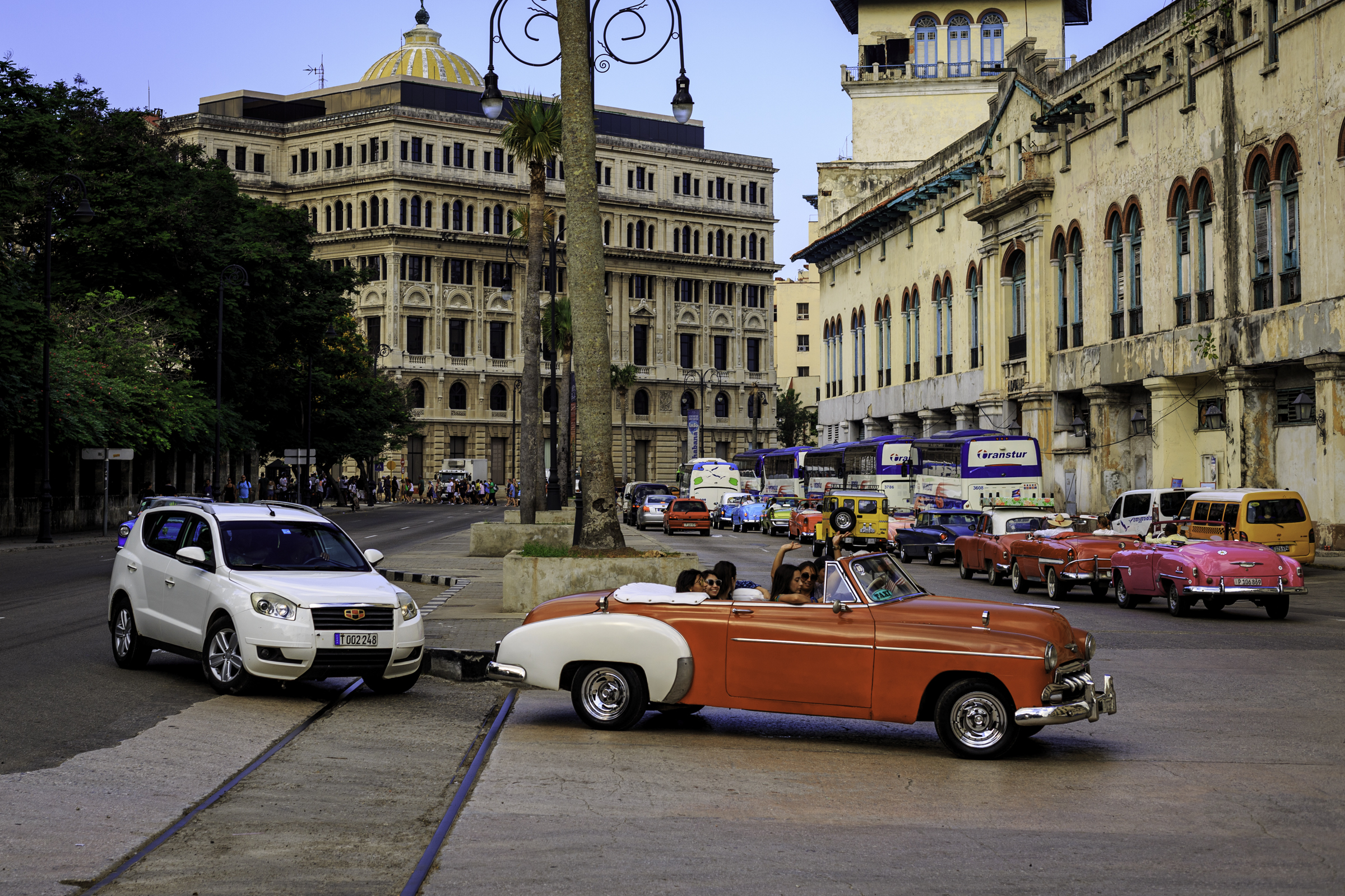 Colorful classic cars, modern vehicles, buses, and historic buildings on a Havana street